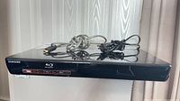 Front and top view of Samsung BD-P3600 Blu-ray player with HDMI and power cables