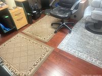 Overview showing two tan rugs and one gray rug on hardwood floor