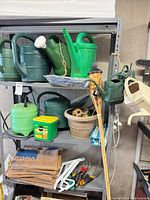 Three-shelf unit with watering cans, sprayer, planter, tiki torch, brackets and yard waste bags