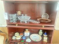 Overall view of two-shelf cabinet showing glassware on top and ceramics on bottom