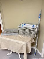 Stack of wire shelf panels, large wire basket, vertical wall track leaned against wall