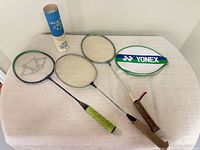 Overview of three badminton rackets, Yonex cover, shuttlecock tube