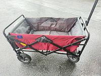 Side view of red and gray folding wagon showing frame, fabric, wheels