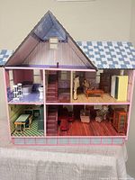 Full view of three-level dollhouse with bedroom, bathroom, living/dining room, kitchen furniture, and two figures