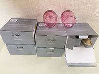 five grey boxes labeled goblets with two pink glasses on top, open box showing packing material