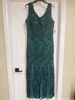 Full front view of teal lace evening dress on hanger
