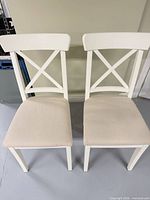 Front view of both chairs showing cross-back frames and upholstery