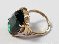Side view of ring showing gold plated setting and large green stone