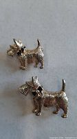 Two gold-tone Scottie dog pins side by side