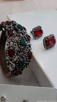 Front view of cuff bracelet showing red and green stones with clear rhinestones and one pair red crystal halo earrings