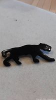 Front view of black plastic jaguar brooch