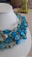 Overall view of multistrand blue bead necklace on display bust