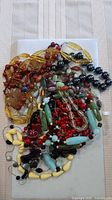 Pile of assorted colourful bead necklaces on board