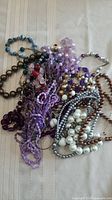 Pile of assorted beaded necklaces in various colours and materials
