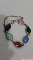 Full view of bracelet showing six coloured scarab cabochons and safety chain