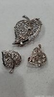 front view of brooch and earrings showing leaf design and rhinestones