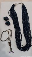 Lot overview showing blue bead necklace, bead earrings, and crystal pendant necklace
