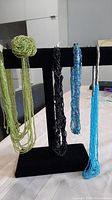 Four multi-strand seed bead necklaces displayed on stand