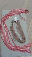 Overview of four pink necklaces, rainbow necklace and earrings