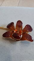 Front view of lacquered orchid brooch pendant with chain