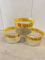 Three clear cylindrical gum holders stacked, showing yellow Adams Chiclets 1¢ bands