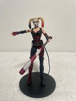 Front view of Harley Quinn figure on stand holding baseball bat