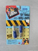 Front of sealed blister pack showing two blue-handled miniature screwdrivers and package graphics