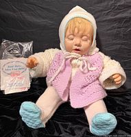 Front view of doll seated, showing clothing and paperwork
