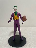 Front view of Joker figure holding mallet on black display base