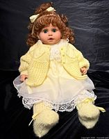 Full view of doll seated showing clothing and overall condition