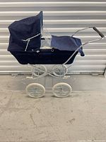 left side view of blue corduroy doll carriage, showing wheels and canopy