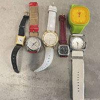 Seven watches laid out showing cases and straps