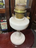 Full view of cream milk glass Aladdin oil lamp with brass burner