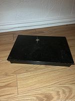 Black metal cash box closed showing top with lock