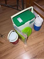 Coleman Oscar cooler, two beverage jugs, packaged air mat, green frisbee