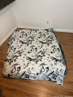 Futon mattress pad folded on floor showing full patterned cover