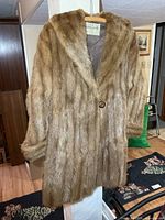 Front view of brown fur coat hanging, showing overall length and fur texture