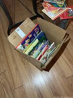 Box of children’s books on floor showing variety of titles