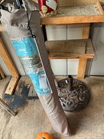 Umbrella in grey carry sleeve next to cast iron base