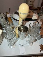 Front view of Hamilton Beach milkshake mixer with stainless cup and four glasses
