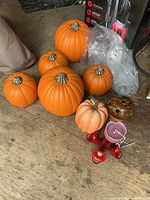 Group view of six plastic pumpkins, foam pumpkin, hummingbird feeder parts and ceramic sphere