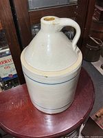 Front view of cream stoneware jug with handle and blue bands