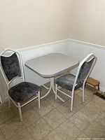 Table and two chairs positioned in corner, showing full set