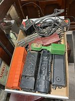 Overview of lot showing locomotive, cars, transformer, track, and signal light in box