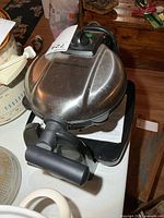 Top view of waffle maker showing stainless lid and handle