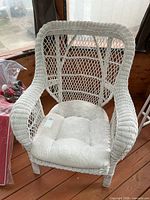 Front view of white wicker armchair with cushion