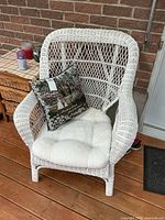 Front view of white wicker armchair with cushion and pillow