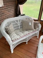 Front view of white wicker loveseat with cushions