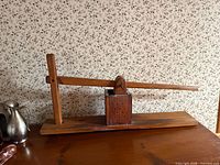 Full view of wooden butter press showing lever, perforated chamber and base