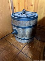 front view of butter churn showing wood staves, metal bands, crank hub and lid